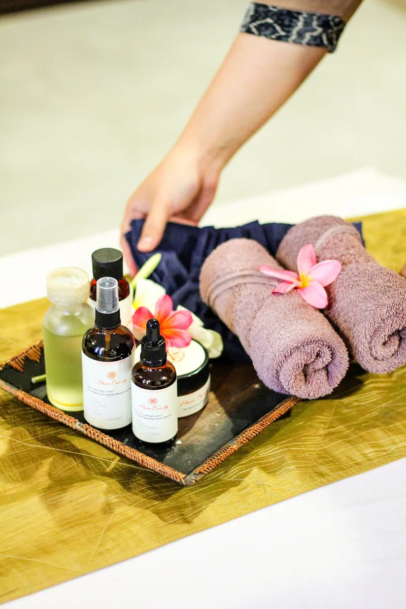 Massage oils, rolled towels and plumeria flowers on a tray (illustrative photo)